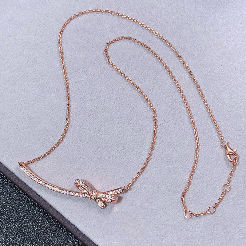 Bow-Knot Motif Full Channel Set Bar Pendant Rose Gold Necklace lay on table