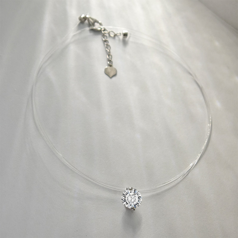 2 Prong Solitaire Pierced Round Cut Floating Set Diamond Necklace With Transparent Plastic Rope lay on table