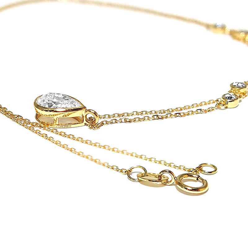 Solitaire Pear Cut Bezel Open Gallery Pendant Alternating Bubble Bezel Accents Diamond Necklace lay on table