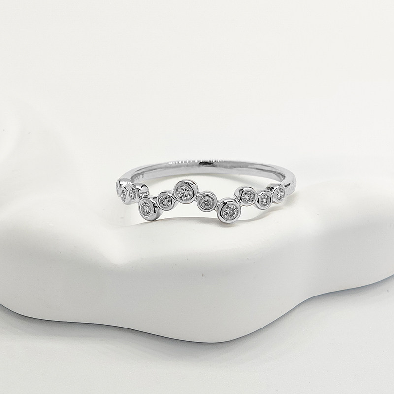 Graduated Bubble Bezel White Gold Synthetic Diamond Contour Stackable Curved Wedding Band lay on table
