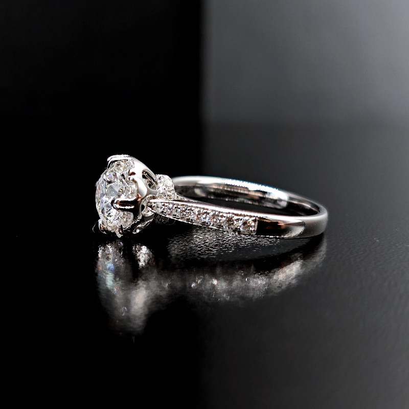 8 Prong Round Cut Halo Diamond Ring With Tapered Shoulder Half Pave Band on desk