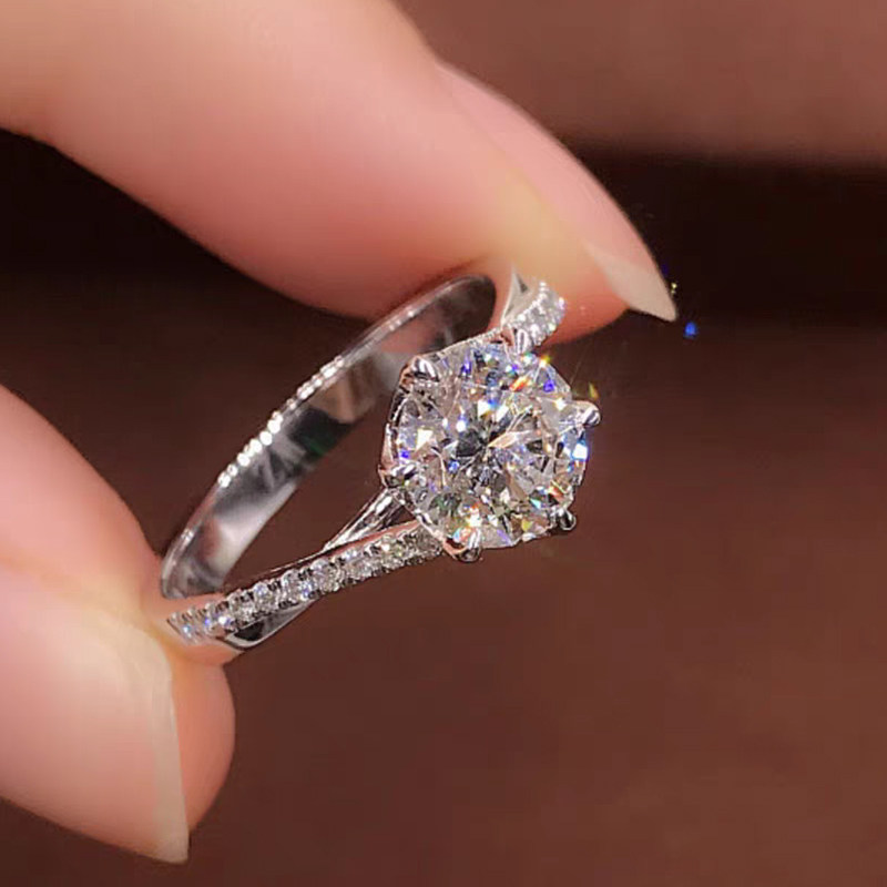 Four Prong Solitaire Hidden Halo Round Diamond Ring With Half Pave Cathedral Shank in hand