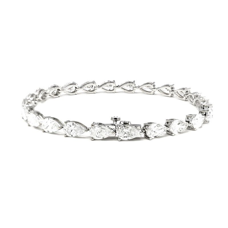 Continuous 3 Prong Pear Cut Diamond Open Gallery & Open Bottom Set Tennis Bracelet lay on table