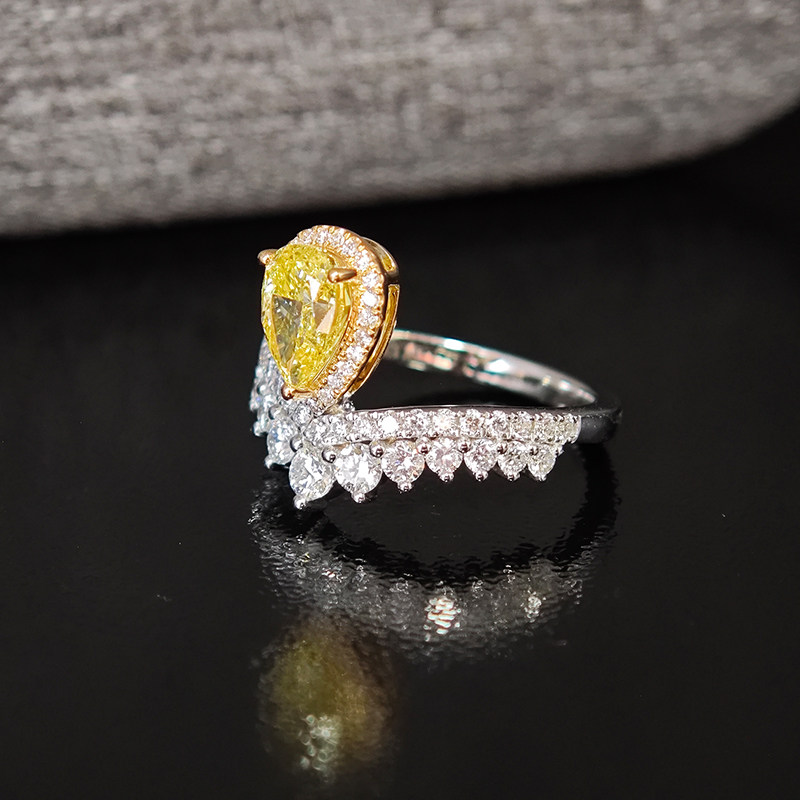 Crown Motif Yellow Pear Cut Halo Diamond Ring With Curved Half Pave Band lie on table